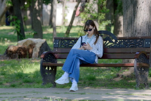 Girl with smartphone relaxing on a bench